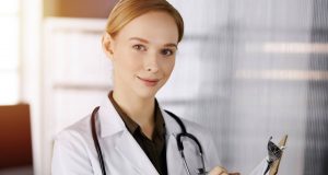 cheerful smiling female doctor using clipboard