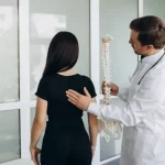 female doctor holding spine model and truing to realize where is patient’s painful place
