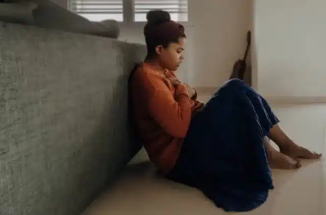 A young woman feeling anxious, resting against a piece of furniture
