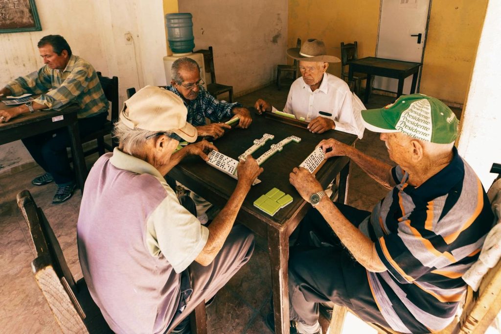 A group of senior men playing dominoes in a relaxed indoor setting, enjoying leisure time.