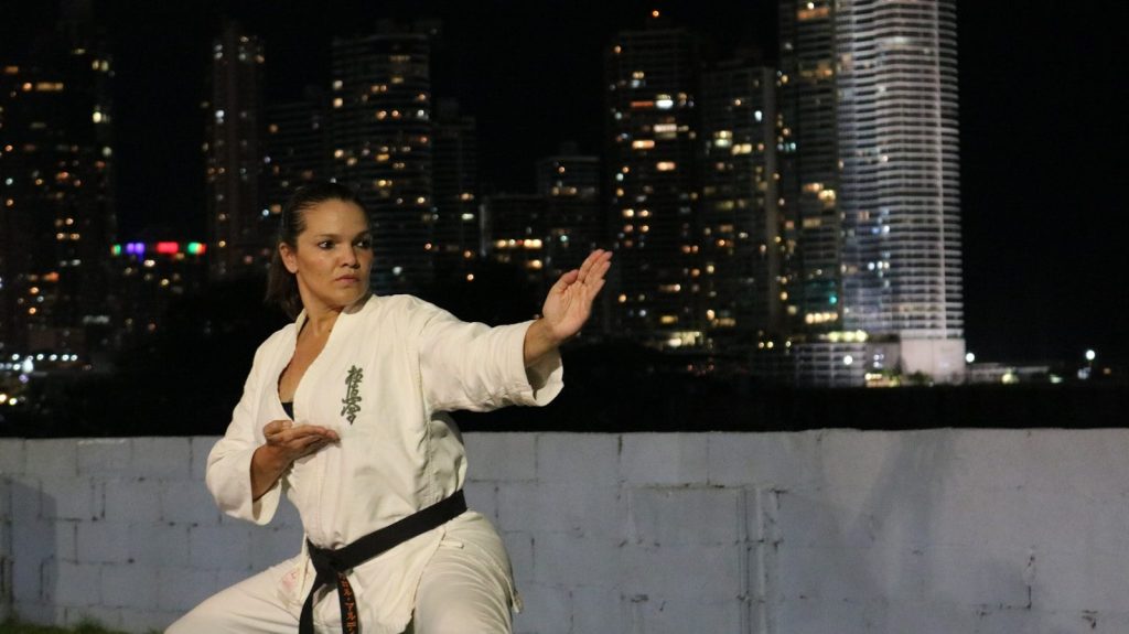 Woman practicing karate in front of city lights