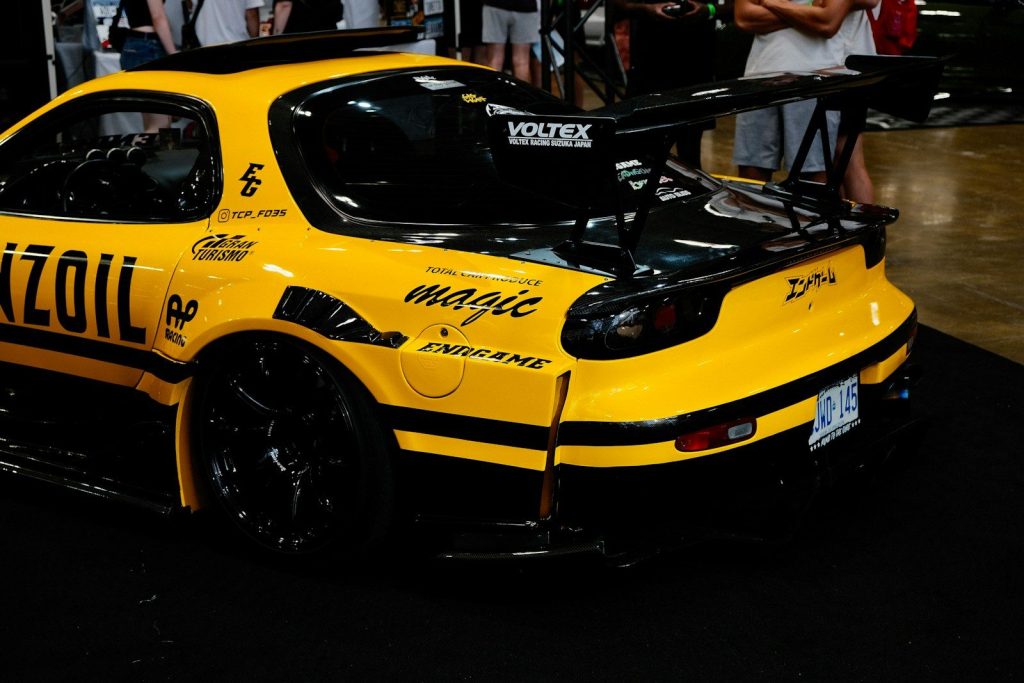 A yellow race car parked in front of a crowd of people