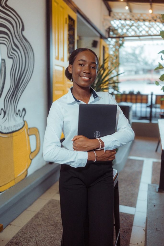 Young woman holding a laptop in front of a mural.