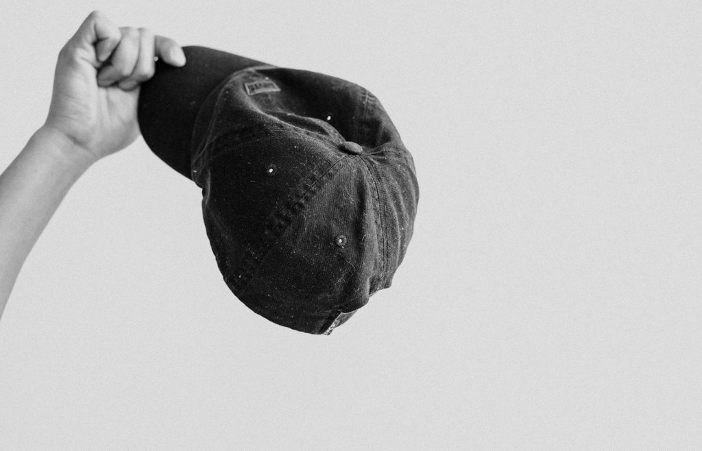 grayscale photo of person holding cap
